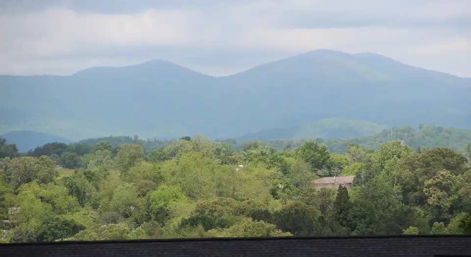 Layered blue ridges of Long Mountain and Gooch Mountain over green treetops, seen from Findley Ridge in Dahlonega