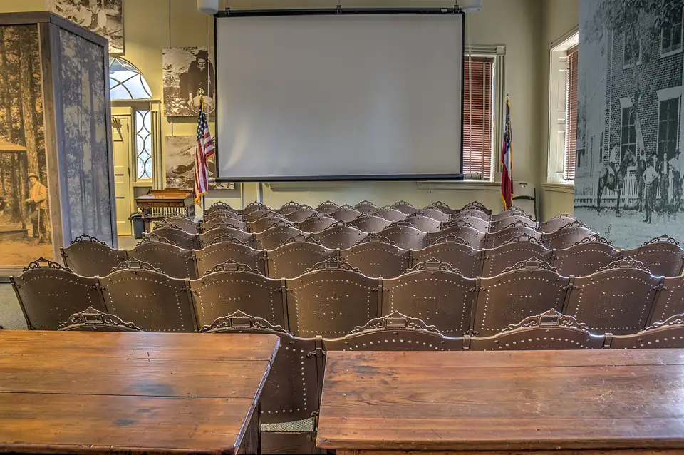 Upstairs courtroom of the 1836 courthouse with rows of pressed-metal seats and two counsel tables