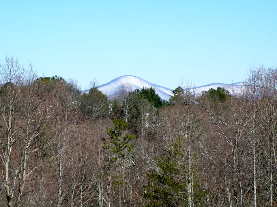 A snow-dusted mountain beyond bare winter woods, seen from the Sky Country area of Dahlonega